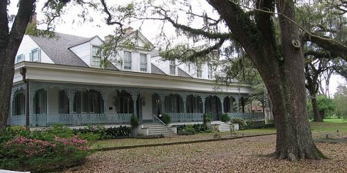 Myrtle Plantation Mansion shaded by trees and Spanish Moss